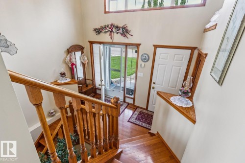 Two-story foyer featuring wood-finish flooring, a wood staircase with balusters, and a transom window above the entry door - 5131 152A Avenue, Edmonton, AB 
