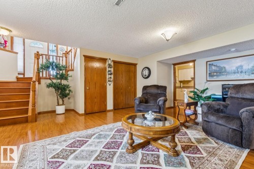 Living area featuring wood-finish flooring, two wood-paneled closet doors, and wood trim detailing - 5131 152A Avenue, Edmonton, AB 