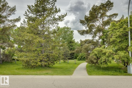 Paved walkway meandering through a lush green space with mature trees - 5131 152A Avenue, Edmonton, AB 