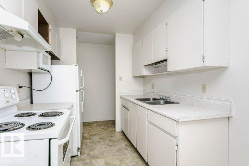 Galley kitchen featuring white cabinetry, laminate countertops, and a double basin stainless steel sink - 71 11255 31 Avenue, Edmonton, AB - Indoor Photo Showing Kitchen With Double Sink