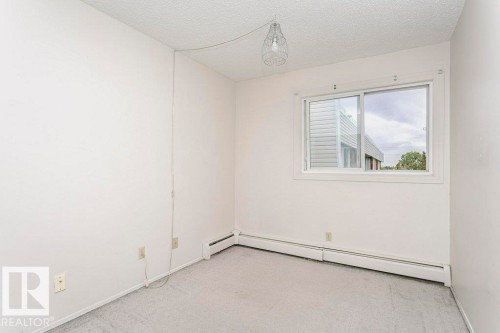 Bright interior room featuring a sliding window, light gray carpet flooring, white walls, and baseboard heating - 71 11255 31 Avenue, Edmonton, AB - Indoor Photo Showing Other Room