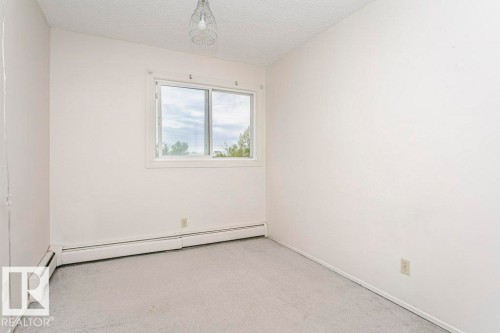 Bright room featuring a prominent window, neutral carpeting, and baseboard heating - 71 11255 31 Avenue, Edmonton, AB - Indoor Photo Showing Other Room