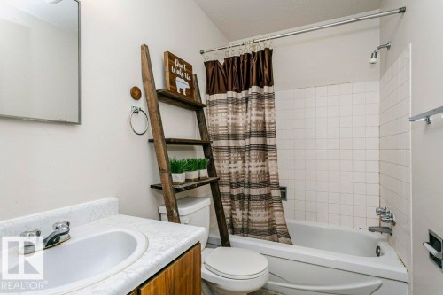 Bathroom featuring a white vanity with a ceramic sink, a chrome faucet, and a large wall mirror - 71 11255 31 Avenue, Edmonton, AB - Indoor Photo Showing Bathroom