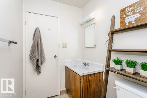 Bathroom vanity featuring a laminate countertop, integrated sink, and wood-finish cabinetry - 71 11255 31 Avenue, Edmonton, AB - Indoor Photo Showing Bathroom