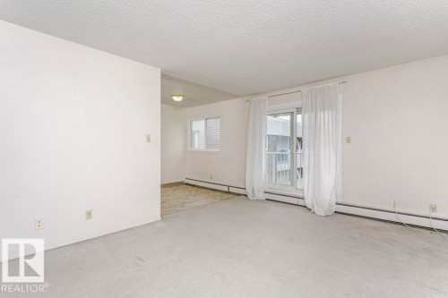 Spacious room featuring light-colored carpeting, white painted walls, and a textured ceiling - 71 11255 31 Avenue, Edmonton, AB - Indoor Photo Showing Other Room