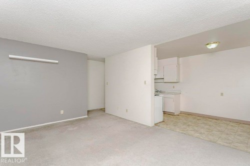 Open concept living area featuring light gray carpeting and a textured ceiling - 71 11255 31 Avenue, Edmonton, AB - Indoor Photo Showing Kitchen