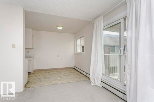 Living area with carpeted flooring, white walls, and a sliding glass door leading to an exterior balcony - 71 11255 31 Avenue, Edmonton, AB - Indoor Photo Showing Other Room