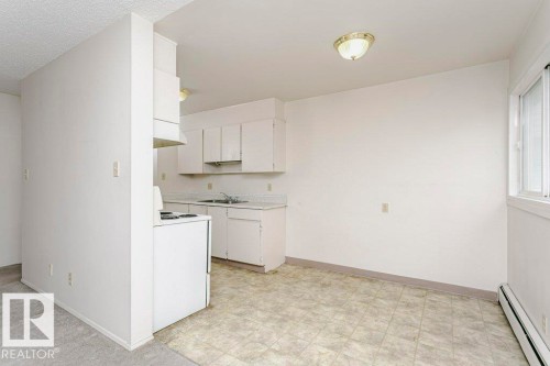 Kitchen area featuring white cabinetry, a double basin sink, and an integrated range hood - 71 11255 31 Avenue, Edmonton, AB - Indoor Photo Showing Kitchen With Double Sink