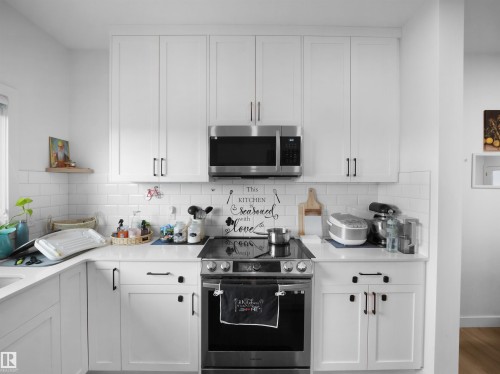 Modern kitchen featuring white shaker cabinetry, stainless steel appliances, white subway tile backsplash, and light-toned countertops - 19316 29 Avenue, Edmonton, AB 