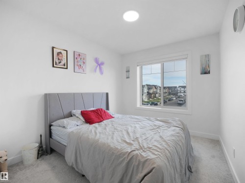 Bright room featuring white walls, a large window, a circular ceiling light fixture, and light-colored carpet flooring - 19316 29 Avenue, Edmonton, AB 