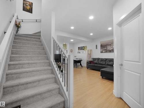 Staircase with gray carpeted treads and white risers, featuring a white handrail with black iron balusters - 19316 29 Avenue, Edmonton, AB 