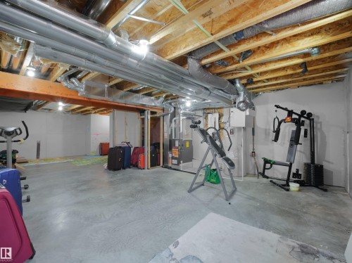 Unfinished basement area featuring exposed ceiling joists, overhead ductwork, concrete flooring, and partial framing - 19316 29 Avenue, Edmonton, AB 