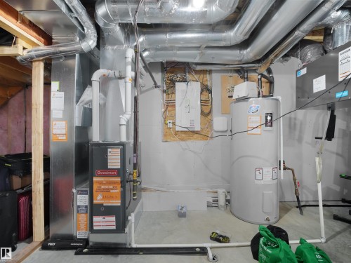 Utility area featuring a Goodman furnace, a water heater, extensive ductwork, and exposed ceiling joists - 19316 29 Avenue, Edmonton, AB 