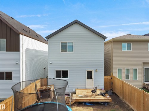 Rear exterior featuring light-colored siding, a wooden deck, and a privacy fence - 19316 29 Avenue, Edmonton, AB 