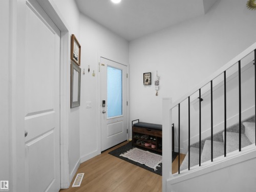 Entryway featuring wood-finish flooring, a white paneled door, and a white front door with frosted glass - 19316 29 Avenue, Edmonton, AB 