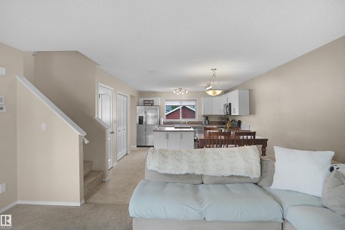 Open-concept living space featuring a stairway with carpeted treads and white handrail - 292 Simmonds Way, Leduc, AB 