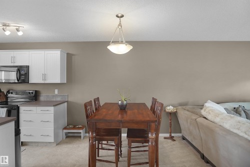 Open-concept dining area featuring a wood-finish table with seating for six, illuminated by a pendant light fixture - 292 Simmonds Way, Leduc, AB 
