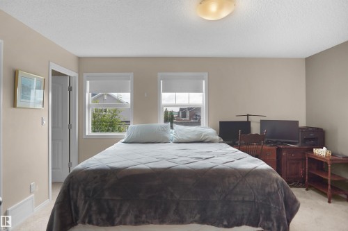 Carpeted room with neutral-toned walls, two windows featuring window treatments, a white door frame, and an overhead flush-mount light fixture - 292 Simmonds Way, Leduc, AB 