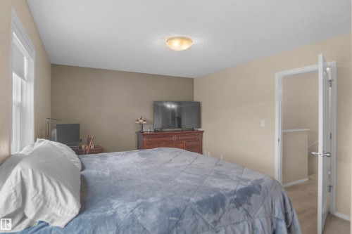 Room featuring neutral wall tones, a textured ceiling, a flush-mount ceiling light, and light-colored carpet flooring - 292 Simmonds Way, Leduc, AB 