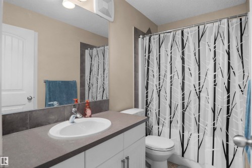 Bathroom featuring a white vanity with an undermount sink, a grey countertop, and a large mirror - 292 Simmonds Way, Leduc, AB 