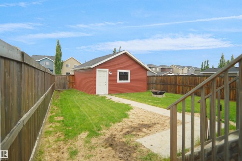Detached red outbuilding with white window trim and a white door - 292 Simmonds Way, Leduc, AB 