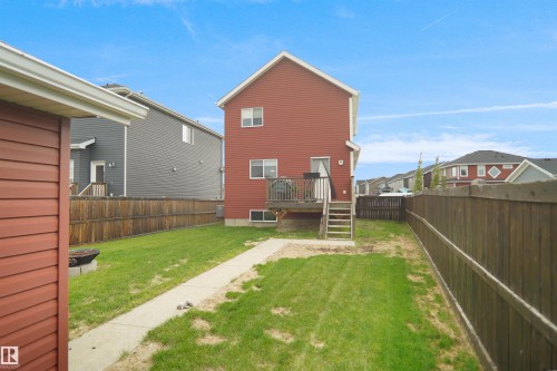 Expansive backyard featuring a manicured lawn, full wood fencing, concrete pathway, and an elevated wood deck with stairs - 292 Simmonds Way, Leduc, AB 