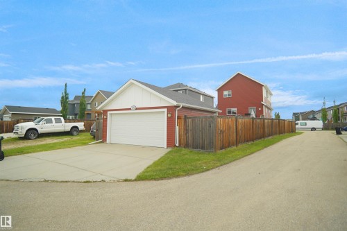 Rear double Detached garage with white overhead door, red siding, and white trim - 292 Simmonds Way, Leduc, AB 