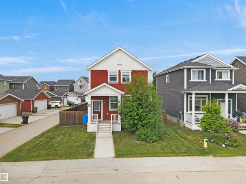 Two-story residence featuring red siding with white trim and a covered front porch - 292 Simmonds Way, Leduc, AB 