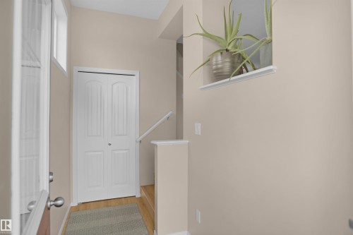Entryway featuring a white bi-fold door, wood-finish flooring, and a window providing natural illumination - 292 Simmonds Way, Leduc, AB 