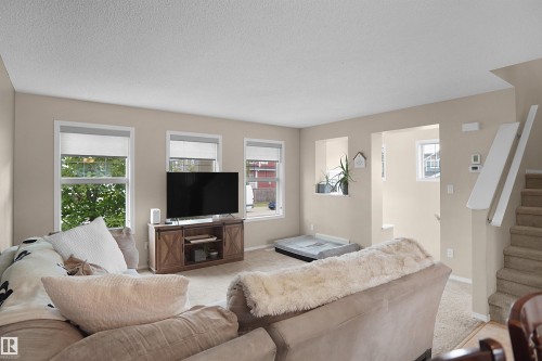 Living area featuring light-toned walls, recessed wall niches, and multiple windows with roller shades - 292 Simmonds Way, Leduc, AB 