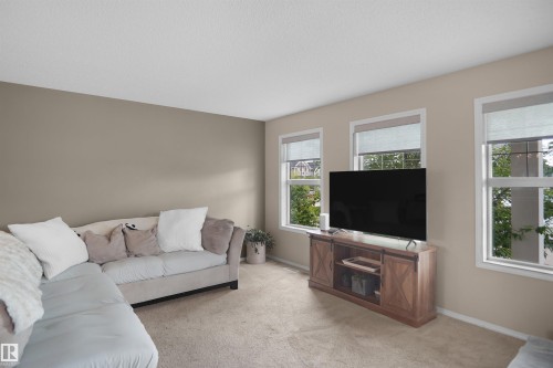 Living space with soft tan wall paint, white trim, and light beige carpeting - 292 Simmonds Way, Leduc, AB 