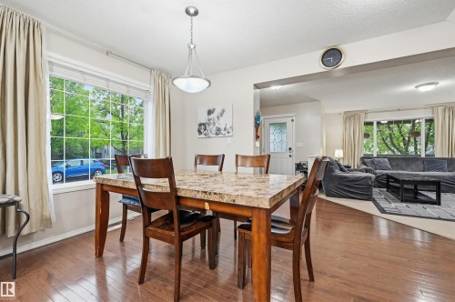 Dining area featuring wood-finish flooring, a large window, and an open entryway to an additional living space - 1804 121 Street, Edmonton, AB 