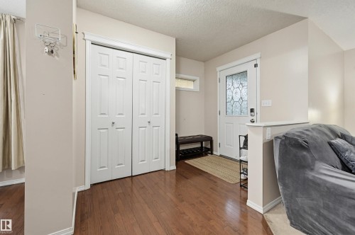Entryway featuring rich wood-finish flooring, a decorative glass-paneled front door, and a transom window - 1804 121 Street, Edmonton, AB 