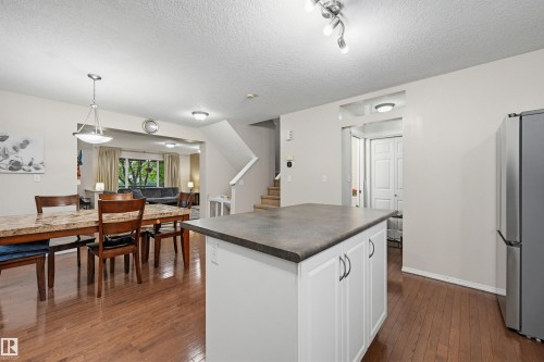Kitchen island with white cabinetry and dark countertop, wood-finish flooring, and recessed lighting - 1804 121 Street, Edmonton, AB 