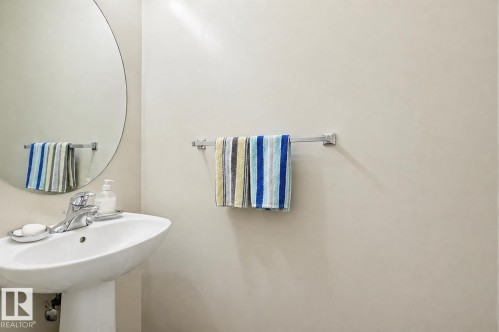 Pedestal sink featuring a polished chrome faucet and a circular wall-mounted mirror - 1804 121 Street, Edmonton, AB 