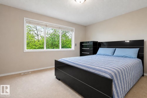 Carpeted room with a wide window, neutral wall paint, and white baseboards - 1804 121 Street, Edmonton, AB 