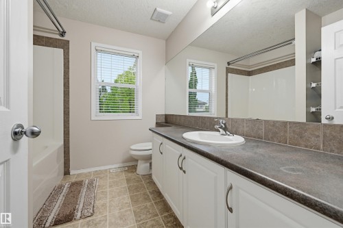 Bathroom featuring a spacious vanity with an integrated sink, ample counter space, white cabinetry, and a full-width mirror - 1804 121 Street, Edmonton, AB 