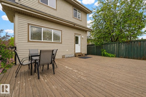 Expansive wood-finish deck with direct exterior access, featuring horizontal siding, multiple windows, and a surrounding privacy fence - 1804 121 Street, Edmonton, AB 