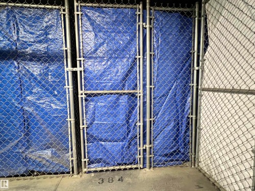 Chain-link fencing with a gate, featuring a blue privacy tarp behind a section of the fence - 140 308 Ambleside Link Link, Edmonton, AB 