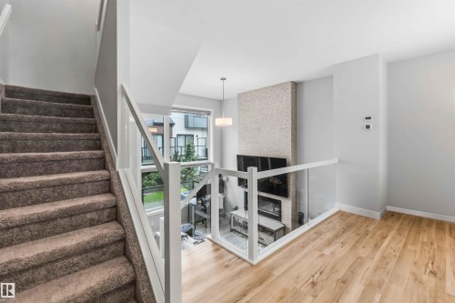 Multi-level living area featuring carpeted stairs, glass panel railings, and wood-finish flooring - 33 1729 Keene Crescent, Edmonton, AB 