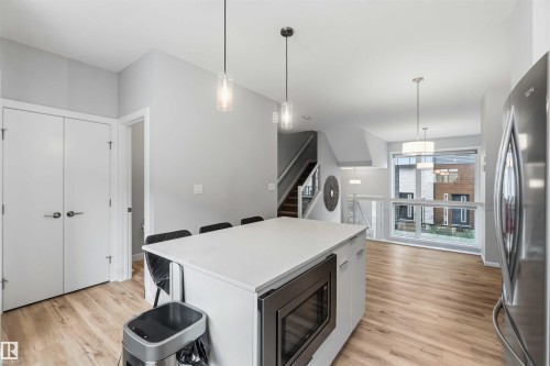 Modern kitchen island featuring a light-colored countertop, integrated microwave, and pendant lighting - 33 1729 Keene Crescent, Edmonton, AB 