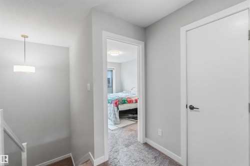 Hallway with light gray wall paint and white trim, featuring a contemporary drum pendant light - 33 1729 Keene Crescent, Edmonton, AB 