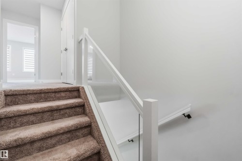 Carpeted staircase with contemporary glass railing and white posts - 33 1729 Keene Crescent, Edmonton, AB 