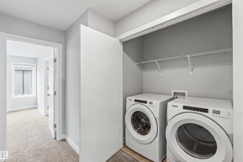 Dedicated laundry closet featuring a front-loading washer and dryer, wire shelving, and overhead lighting - 33 1729 Keene Crescent, Edmonton, AB 