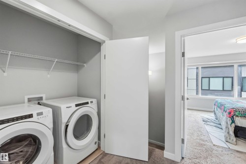 Dedicated laundry closet featuring a stacked washer and dryer, wire shelving, and neutral wall finishes - 33 1729 Keene Crescent, Edmonton, AB 