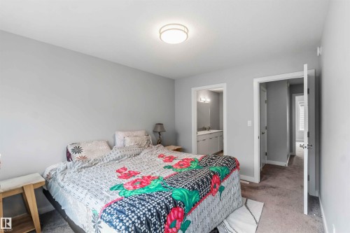 Carpeted bedroom featuring light gray walls, a flush-mount ceiling light fixture, and two doorways - 33 1729 Keene Crescent, Edmonton, AB 