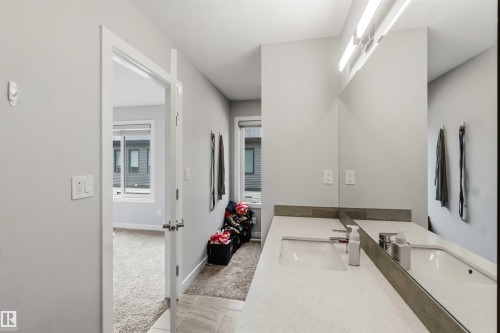 Dual vanity featuring integrated sinks, expansive counter space, a full-width mirror, and overhead strip lighting - 33 1729 Keene Crescent, Edmonton, AB 