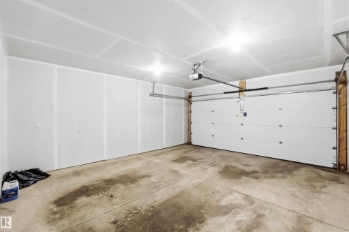 Two-car garage featuring a concrete floor, white panel garage door, automatic garage door opener, and overhead lighting - 33 1729 Keene Crescent, Edmonton, AB 