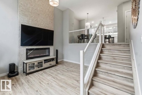 Contemporary interior featuring light wood-finish flooring and a staircase with a glass and white railing - 33 1729 Keene Crescent, Edmonton, AB 