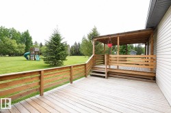 Expansive wood deck featuring a covered porch area, wood railings, and a side entrance with stairs - 